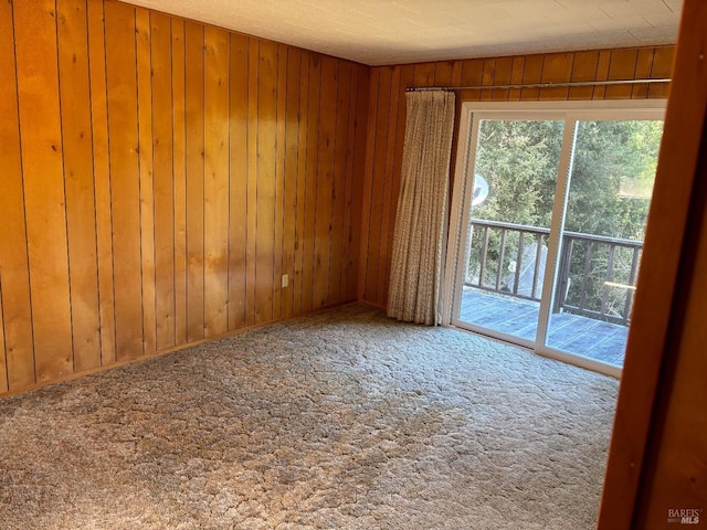 carpeted empty room featuring wooden walls