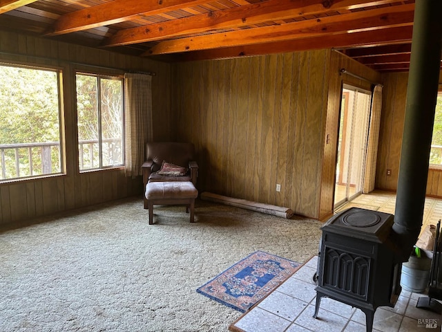 sitting room with beamed ceiling, wooden ceiling, a wood stove, and wooden walls