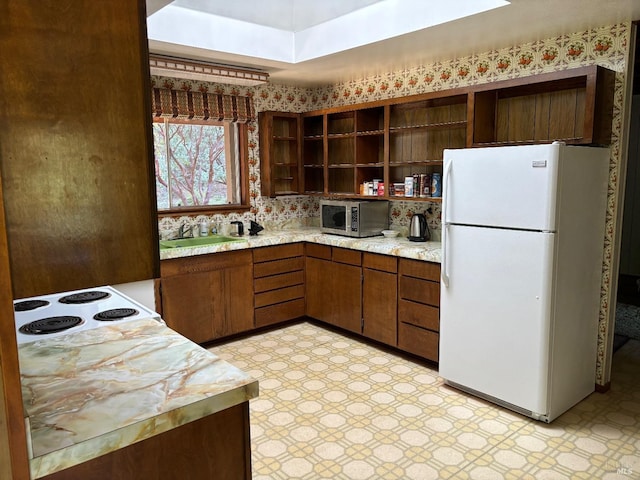 kitchen with white refrigerator, sink, light tile floors, and stove