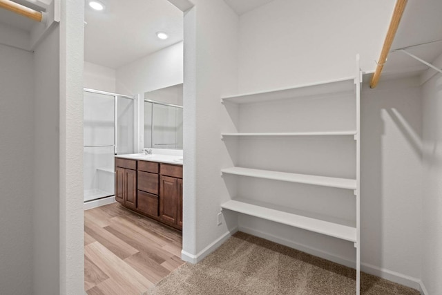 walk in closet with light hardwood / wood-style floors and sink