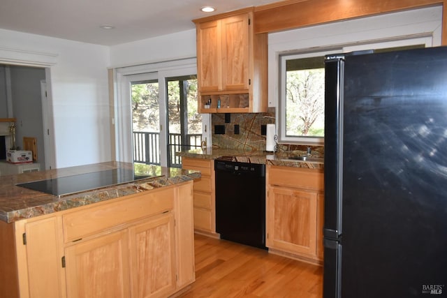 kitchen with backsplash, sink, black appliances, and light wood-type flooring