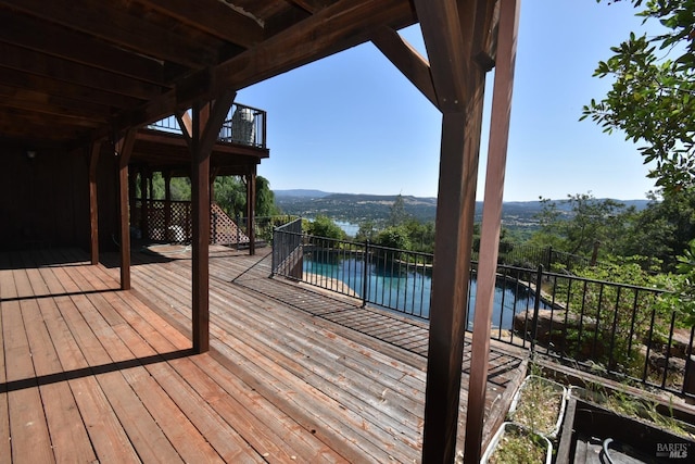 wooden deck featuring a water view and a fenced in pool