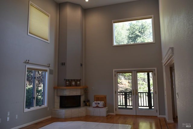 unfurnished living room featuring hardwood / wood-style floors, a high ceiling, and a tile fireplace