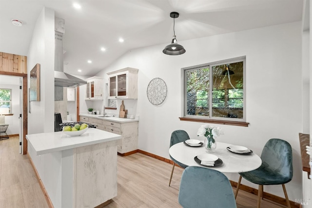 kitchen featuring a sink, light wood-style floors, white cabinets, light countertops, and glass insert cabinets