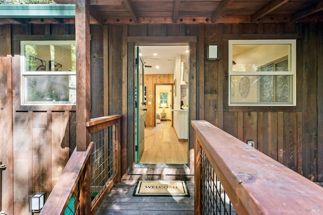 hallway with wood walls, wood ceiling, beam ceiling, and wood finished floors