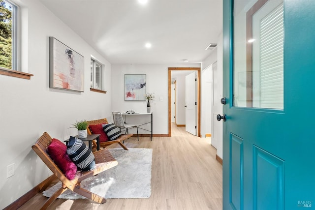 hall featuring light wood finished floors, visible vents, and baseboards