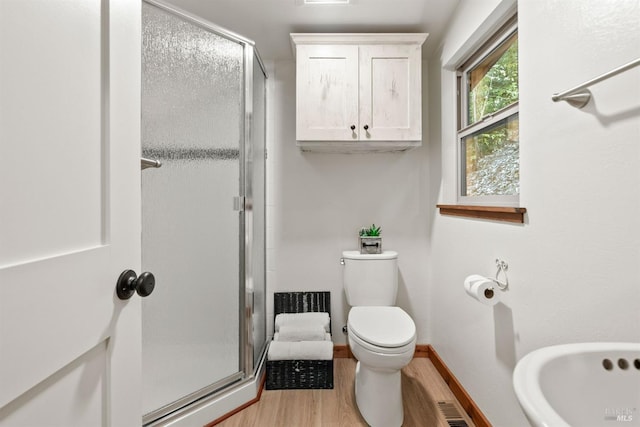 full bathroom with a stall shower, baseboards, toilet, and wood finished floors