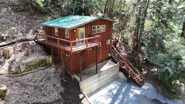 back of property featuring metal roof, stairway, and a wooden deck