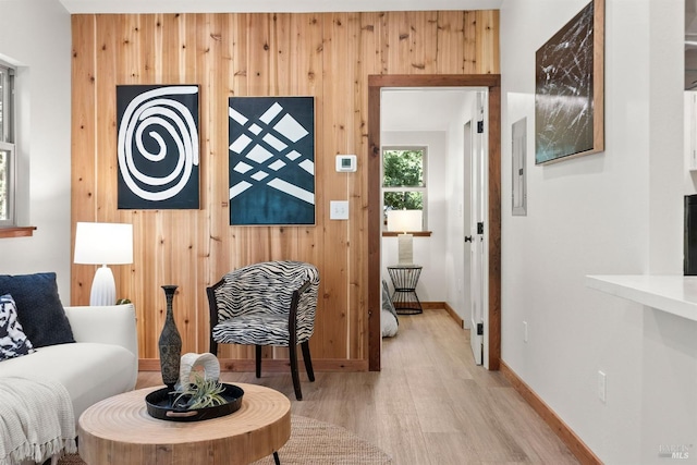 sitting room featuring light wood finished floors, wood walls, and baseboards