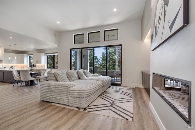 living room with light hardwood / wood-style flooring, a towering ceiling, and plenty of natural light