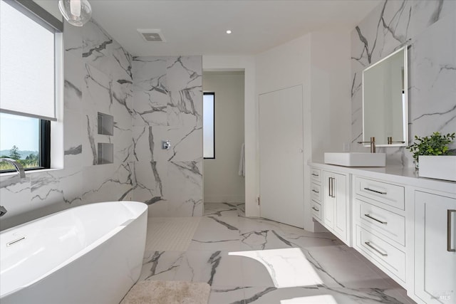 bathroom featuring a washtub, vanity, tile floors, and tile walls