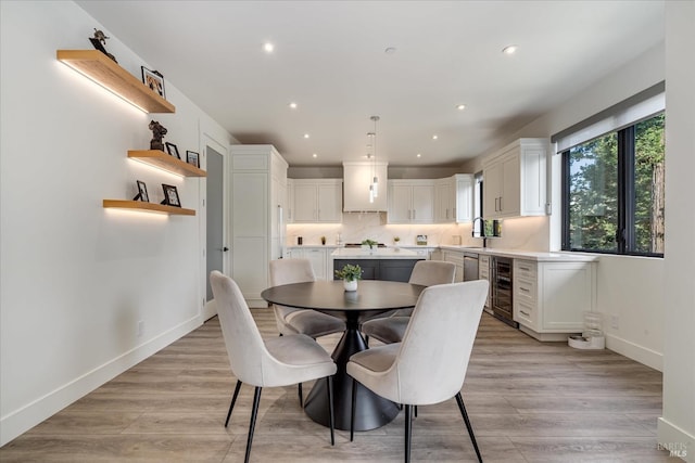 dining space with beverage cooler and light hardwood / wood-style floors