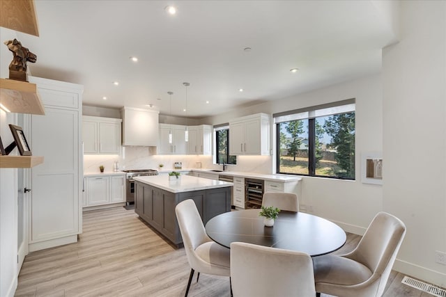 dining room with beverage cooler, sink, and light hardwood / wood-style flooring