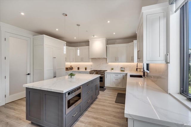 kitchen with light stone counters, a kitchen island, tasteful backsplash, stainless steel appliances, and premium range hood