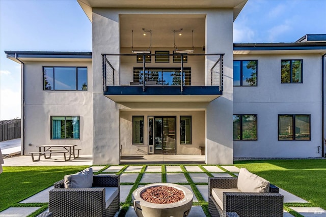 rear view of house featuring a patio, a yard, a balcony, and an outdoor living space with a fire pit