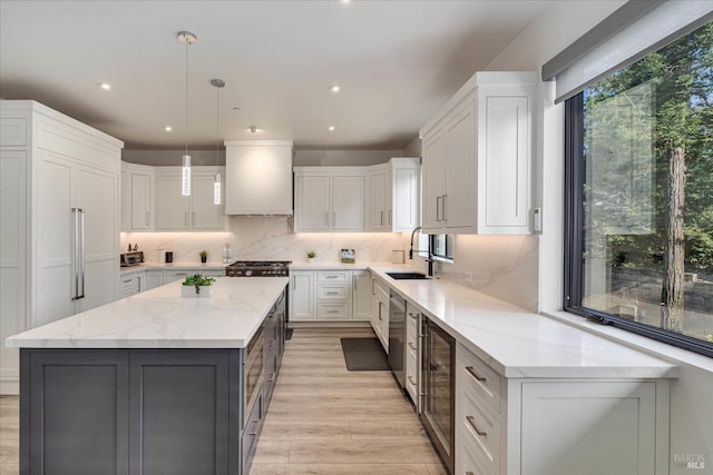 kitchen with light stone counters, a kitchen island, backsplash, white cabinetry, and premium range hood