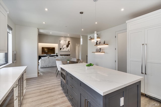 kitchen featuring decorative light fixtures, light hardwood / wood-style floors, white cabinetry, and a kitchen island