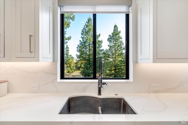 kitchen featuring white cabinets, sink, and light stone countertops