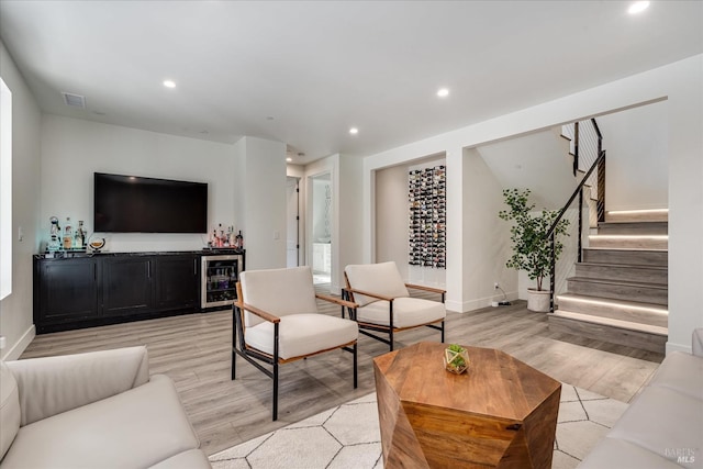 living room featuring wine cooler, bar, and light hardwood / wood-style floors