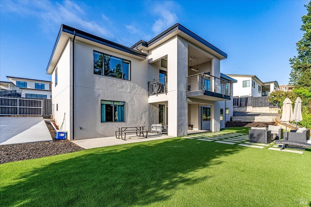 rear view of property featuring a patio area, a balcony, and a lawn