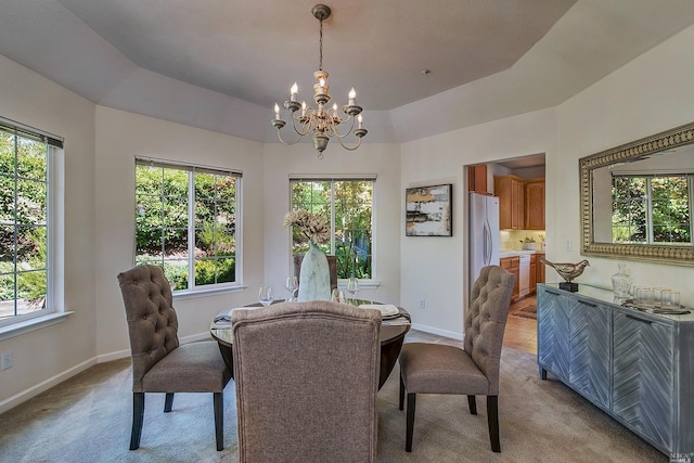 carpeted dining space with a notable chandelier and a tray ceiling