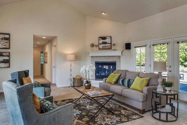 living room with carpet floors, a tiled fireplace, and high vaulted ceiling