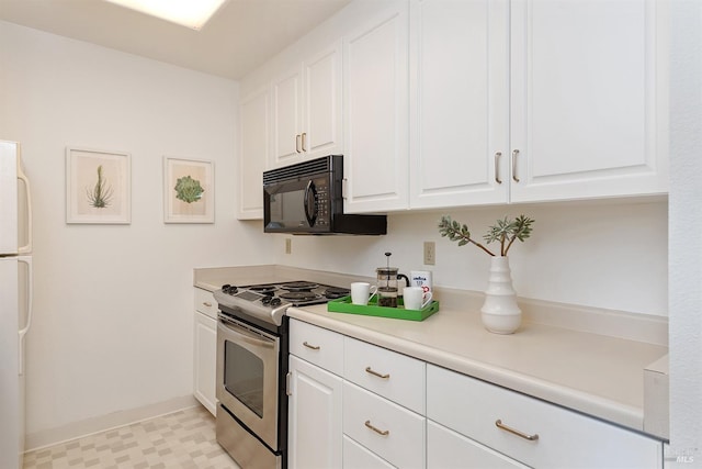 kitchen featuring white refrigerator, white cabinetry, light tile flooring, and stainless steel gas range oven