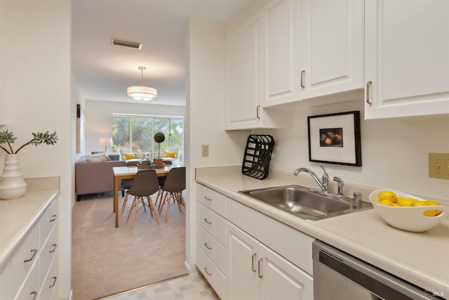 kitchen featuring light colored carpet, decorative light fixtures, white cabinets, sink, and stainless steel dishwasher