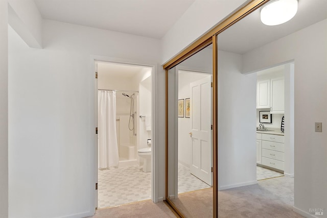 hall featuring light colored carpet and sink