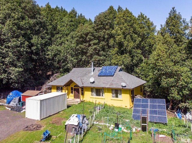 27651 Skyview Rd, Willits, CA 95490 - back of house with ground mounted solar panels, stucco siding, a shingled roof, and a wooded view