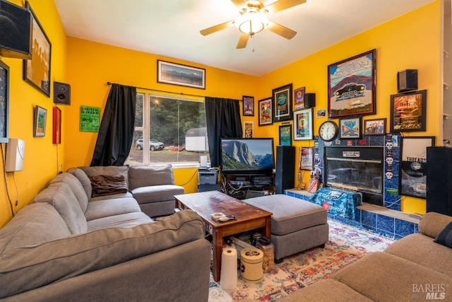 tiled living room with ceiling fan and a tile fireplace