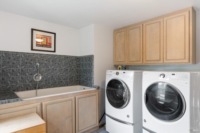 clothes washing area featuring independent washer and dryer and cabinets