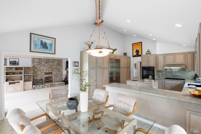 dining room with light hardwood / wood-style flooring, high vaulted ceiling, sink, and a fireplace