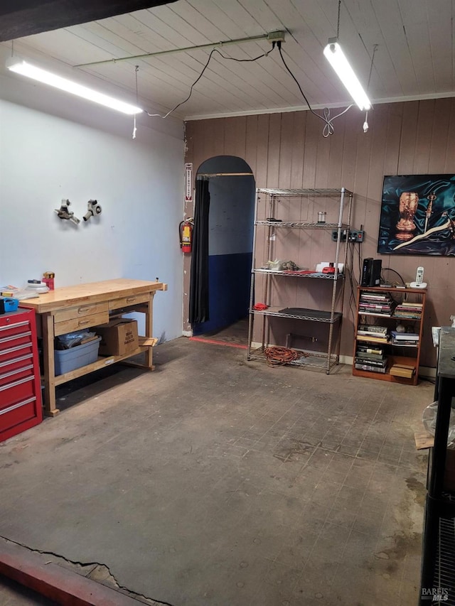 basement with a workshop area and wooden walls