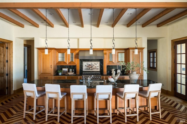 kitchen featuring pendant lighting, a kitchen bar, decorative backsplash, and premium range hood