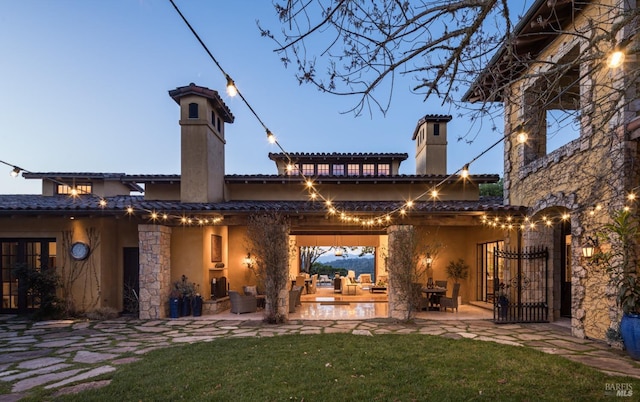 back house at dusk featuring a patio