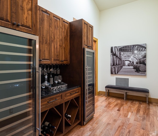 kitchen with dark brown cabinets, beverage cooler, and light hardwood / wood-style flooring