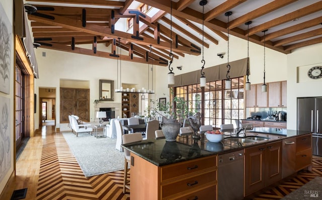 kitchen featuring sink, decorative light fixtures, stainless steel fridge, dishwasher, and a kitchen island with sink