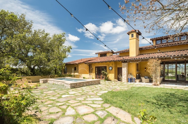 rear view of property featuring a swimming pool with hot tub, a yard, and a patio area