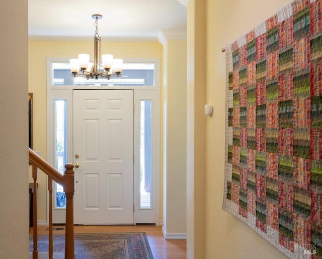 entrance foyer featuring crown molding, hardwood / wood-style floors, and a chandelier