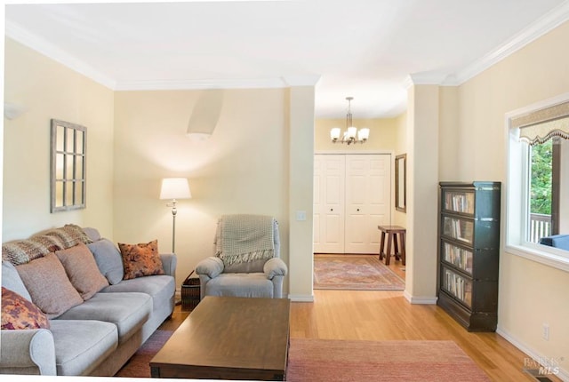 living room with a notable chandelier, ornamental molding, and light wood-type flooring