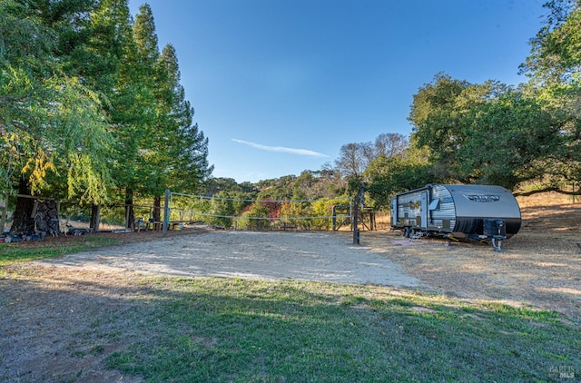 view of car parking with a yard and volleyball court