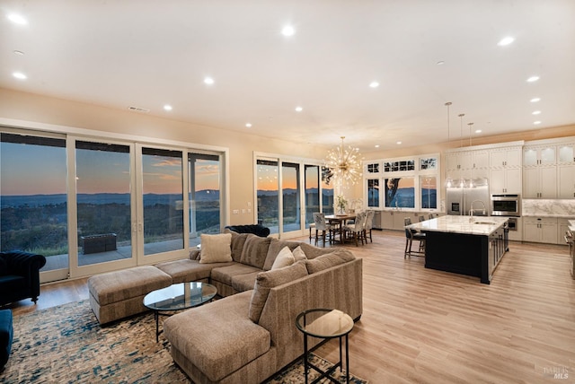 living room featuring sink, light hardwood / wood-style floors, and an inviting chandelier