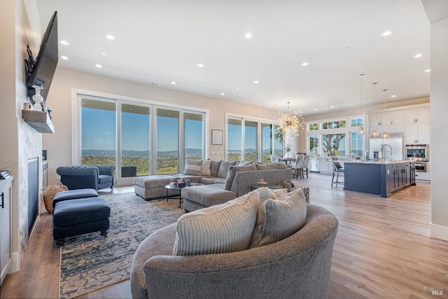 living room featuring a chandelier, light hardwood / wood-style flooring, and sink