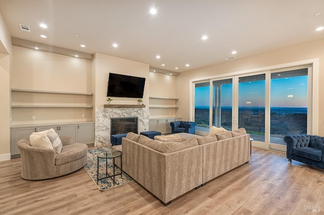 living room with light hardwood / wood-style flooring and a premium fireplace