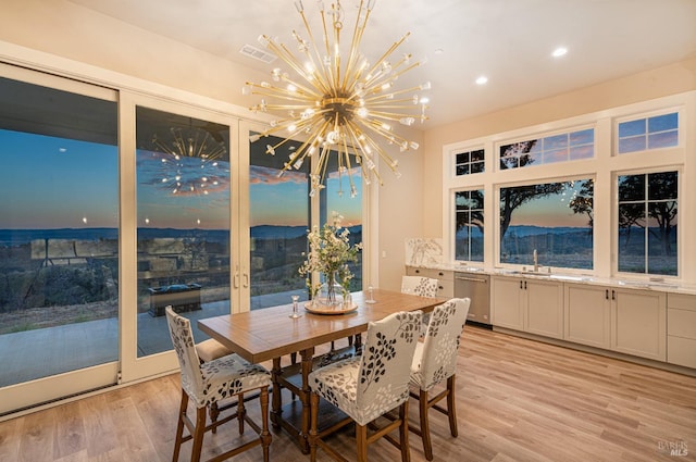 dining room with sink, a notable chandelier, and light wood-type flooring