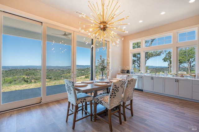 dining room with wood-type flooring, a wealth of natural light, and a notable chandelier