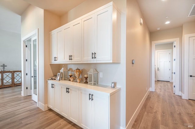 bar featuring light hardwood / wood-style floors and white cabinetry