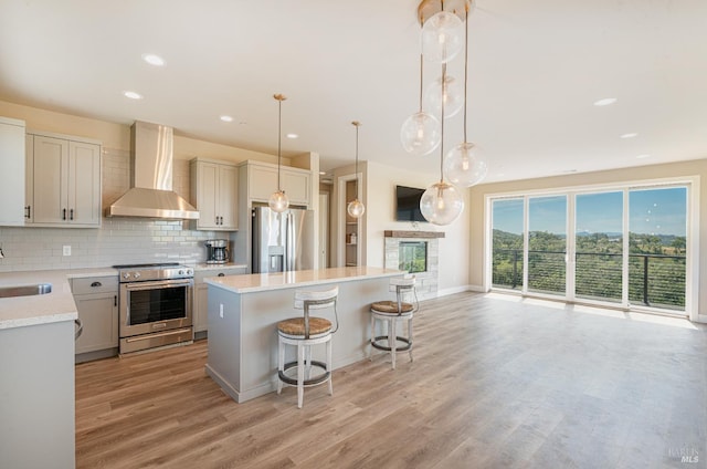 kitchen with hardwood / wood-style floors, a center island, white cabinets, wall chimney range hood, and appliances with stainless steel finishes