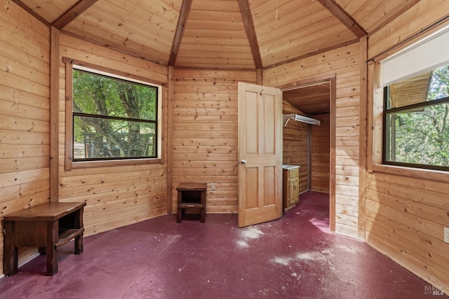 unfurnished room featuring vaulted ceiling, wooden walls, and wooden ceiling